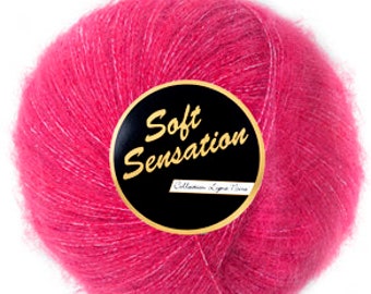 Puede incluir: Un ovillo de hilo rosa con una etiqueta que dice "Soft Sensation" en letras doradas sobre fondo negro.