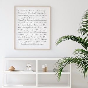 May include: A framed print with a white background and black text. The text reads: "Be nice be kind and loving. Remember the best in people. Start being better now. This moment not tomorrow. not on Monday. Be the best version of yourself. There is no time to live later live in the moment right now. Give the best of you to others and never wait for them to give something in return. Be the first to say I'm sorry, be the first to share a smile. There is enough hate in this world. You become the change."