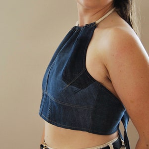 Puede incluir: Un top halter de mezclilla azul con un lazo de cuerda blanco. El top es corto y tiene una silueta ajustada.