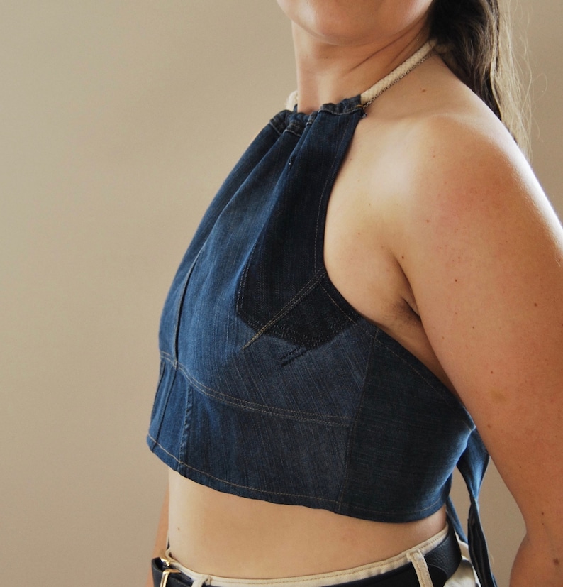 Puede incluir: Un top halter de mezclilla azul con un lazo de cuerda blanco. El top es corto y tiene una silueta ajustada.