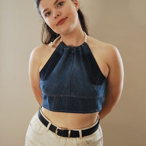 Puede incluir: Una mujer con un top halter de mezclilla azul con un lazo de cuerda blanco, un cintur&oacute;n negro y pantalones cortos de mezclilla blancos.