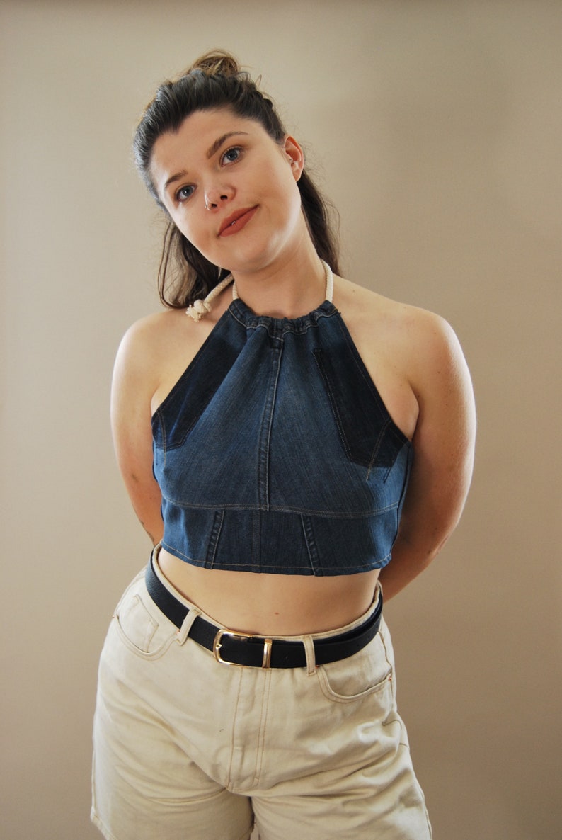 Puede incluir: Una mujer con un top halter de mezclilla azul con un lazo de cuerda blanco, un cintur&oacute;n negro y pantalones cortos de mezclilla blancos.