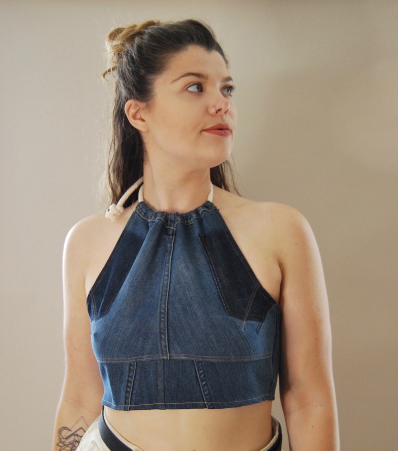 Puede incluir: Un top halter de mezclilla con un escote fruncido y tirantes ajustables. El top es corto y est&aacute; hecho de tela de mezclilla azul.