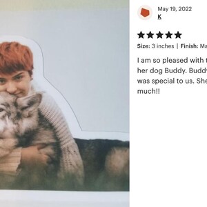 A person is sitting on the ground and hugging a dog, with a rating and comment expressing their appreciation for the dog's memorial.