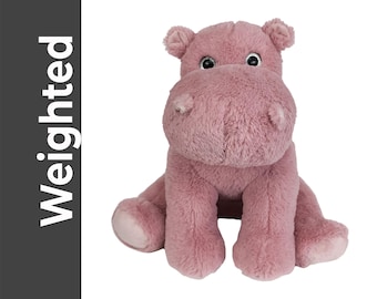 May include: A plush, pink hippo toy with a soft, fuzzy texture. The hippo has large, shiny eyes and is sitting with its legs extended. The word "Weighted" is printed vertically in white on a dark gray background.