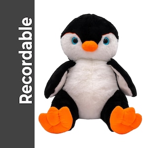 A plush penguin toy with a black and white body, orange feet, and blue eyes is sitting on a white background.