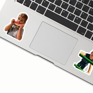 two stickers of children on a laptop keyboard.