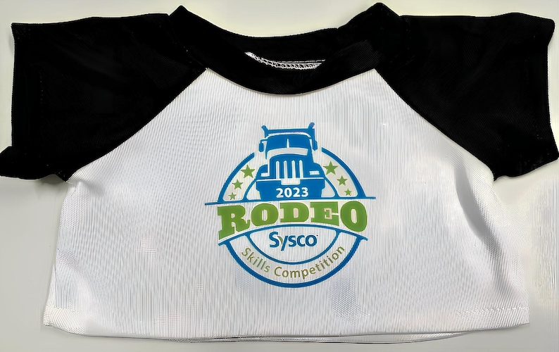 A white t-shirt with a black sleeve and a graphic design featuring a truck and the text "Rodeo Skills Competition" printed on it.