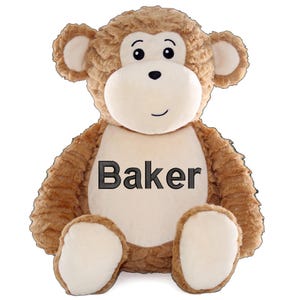 May include: A plush brown monkey with a cream-colored face, hands, and feet. The monkey has a friendly expression with black eyes and a small smile. The name "Baker" is embroidered in black on the monkey's chest. A cuddly stuffed animal.