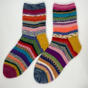 May include: Two pairs of colorful striped socks with a yellow heel and toe. The socks are made of a soft, knitted fabric.