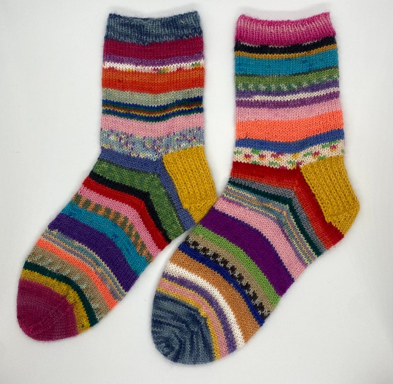 May include: Two pairs of colorful striped socks with a yellow heel and toe. The socks are made of a soft, knitted fabric.