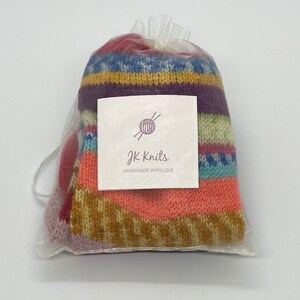 May include: A colorful striped knitted item in a clear organza bag with a white tag that says "JK Knits handmade with love".