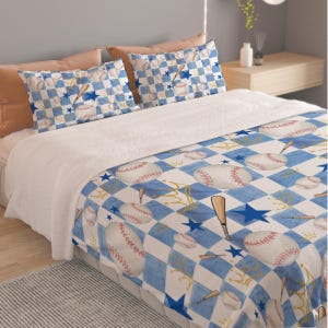 May include: A bedding set featuring a white and blue checkered pattern with illustrations of baseballs, wooden bats, blue stars, and gold crowns. The set includes a large comforter and two matching pillowcases, all displaying the same sports-themed design.