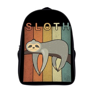 May include: Black backpack featuring a cartoon sloth design. The sloth is gray and hangs from a brown branch against a retro-style striped background in orange, yellow, and teal. The word "SLOTH" is printed above the sloth.