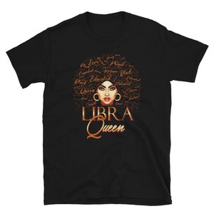 May include: Black t-shirt featuring a brown illustration of a woman's face with an afro hairstyle. The afro is made up of words describing a strong, confident woman. The words "LIBRA QUEEN" are written below the illustration.