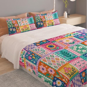 May include: A bedding set featuring a quilt and two pillowcases with a vibrant patchwork design. The pattern consists of colourful squares displaying various floral motifs, daisies, sunflowers, and geometric shapes in shades of pink, orange, yellow, blue, and green.