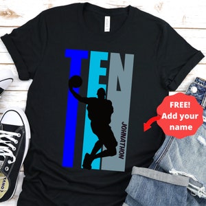 May include: Black t-shirt with a blue, teal, and gray graphic of a basketball player dunking with the word 