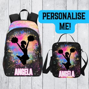 May include: A black backpack and lunch bag set with a cheerleader silhouette and pom-poms against a colourful galaxy backdrop. The name "ANGELA" is in pink. The text "PERSONALISE ME!" is in a blue box.