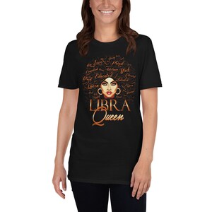 May include: Black t-shirt featuring a brown illustration of a woman's face with the words "LIBRA Queen" underneath. The woman's hair is styled as an afro with words such as "Love", "Queen", "Educated", and "Talented" written on it.
