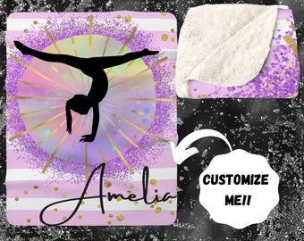 May include: A pink and white striped fleece blanket with a purple glitter background. A silhouette of a gymnast doing a handstand is in the centre of the blanket. The words "Amelia" are written in gold script at the bottom of the blanket.
