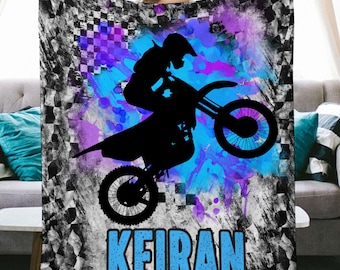 Puede incluir: Un fondo a cuadros blanco y negro con salpicaduras de acuarela azul y púrpura. Una silueta de una persona montando una moto de cross salta sobre las salpicaduras. El nombre "KEIRAN" está escrito en letras azules en la parte inferior de la imagen.