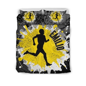 May include: A bedding set featuring a duvet cover and two pillowcases with a black, white, and yellow paint splatter design. The center displays a black silhouette of a runner and the name EMILIO. The pillowcases feature a runner and the text EAT, SLEEP, SPORTS, REPEAT.