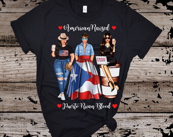 May include: Black t-shirt with a graphic of three women, one wearing a Puerto Rican flag skirt, another wearing a USA flag shirt, and the third wearing a black dress. The text "American Raised Puerto Rican Blood" is printed on the shirt.