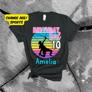May include: Black t-shirt with a rainbow sunset graphic featuring a silhouette of a person holding a bow and arrow. The text "Birthday Girl 10 Amelia" is printed on the shirt.