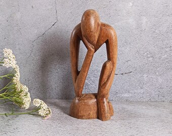 Scultura astratta in legno intagliata a mano raffigurante un uomo pensieroso.