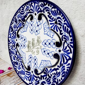 May include: A large, round ceramic plate with a blue and white floral design. The centre of the plate features a silver-coloured design of three owls perched on a branch. The plate is ideal for serving food or as a decorative piece.