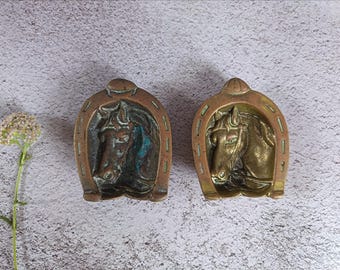 Coppia di piattini portagioie vintage in ottone massiccio a forma di testa di cavallo e ferro di cavallo.