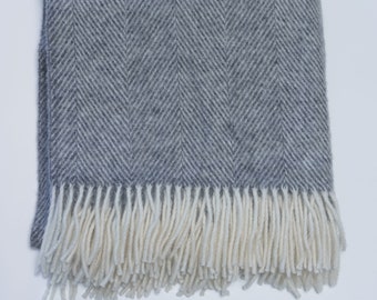May include: A gray herringbone throw blanket with a white fringe.