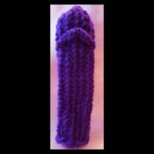 Puede incluir: Un artículo tejido a mano, en un vibrante tono púrpura. La forma cilíndrica tiene una parte superior redondeada y un patrón acanalado texturizado. El artículo parece ser un accesorio acogedor y artesanal.