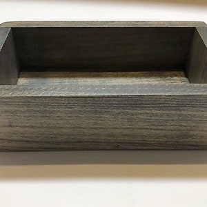 May include: A rectangular wooden box with a gray wash finish. The box has a simple design and is perfect for storing small items.