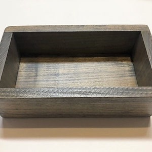 May include: A rectangular wooden box with a gray stain finish. The box has a simple design with a rectangular opening and a smooth, even surface.