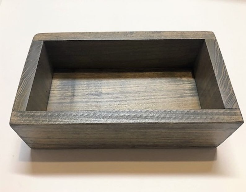 May include: A rectangular wooden box with a gray stain finish. The box has a simple design with a rectangular opening and a smooth, even surface.