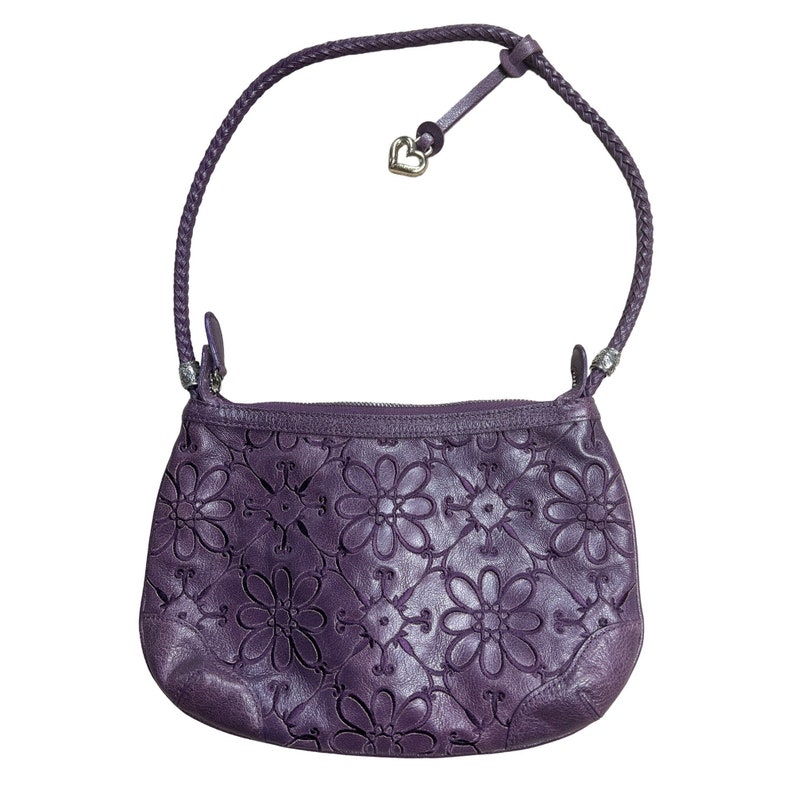 May include: A purple leather handbag with a floral design and a heart-shaped charm.