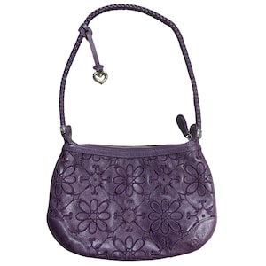 May include: A purple leather handbag with a braided strap and a floral embossed design. The bag has a heart-shaped charm attached to the strap.
