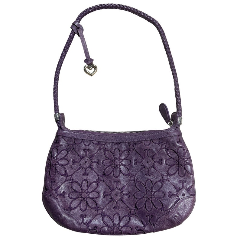 May include: A purple leather handbag with a braided strap and a floral embossed design. The bag has a heart-shaped charm attached to the strap.