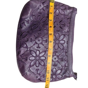 May include: A purple leather clutch bag with a floral design. The bag is approximately 11 inches long.