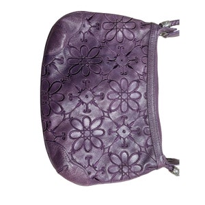 May include: A purple leather shoulder bag with a floral embossed design. The bag has a zip closure and a strap.