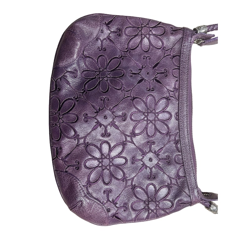 May include: A purple leather shoulder bag with a floral embossed design. The bag has a zip closure and a strap.