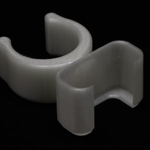 以下が含まれることがあります： 2つの開口部のある白いプラスチック製のパイプクランプ。クランプはパイプを一緒に保持するように設計されています。