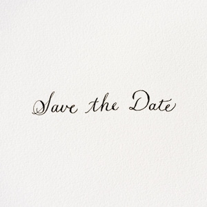 May include: A white card with the phrase "Save the Date" written in elegant black cursive script. The text is centered, and the background is a textured, off-white color.