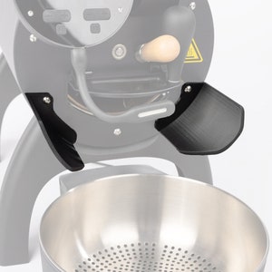 Könnte beinhalten: Schwarzer Kaffeeröster mit einem Auffangbehälter aus Edelstahl. Der Röster hat zwei schwarze Seitenpaneele, die helfen, die Kaffeebohnen in den Auffangbehälter zu leiten.