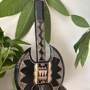 May include: A black wooden axe with a gold-colored design. The axe has a carved handle and the word "HAWAII" is written on the blade.