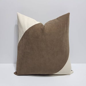 May include: A brown and cream colored throw pillow with a geometric design. The pillow is made of a soft, plush fabric.