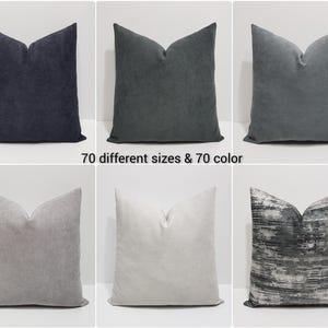 May include: A collection of six square throw pillows in various shades of gray, ranging from dark charcoal to light silver, with one featuring a black and white abstract horizontal striped pattern. The text 70 different sizes & 70 color is visible.