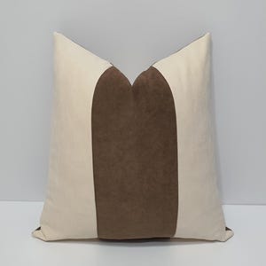 May include: A decorative throw pillow with a brown velvet stripe down the center and white fabric on either side.