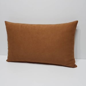 Könnte beinhalten: Ein rechteckiges braunes Kissen mit weichem, strukturiertem Stoff.
